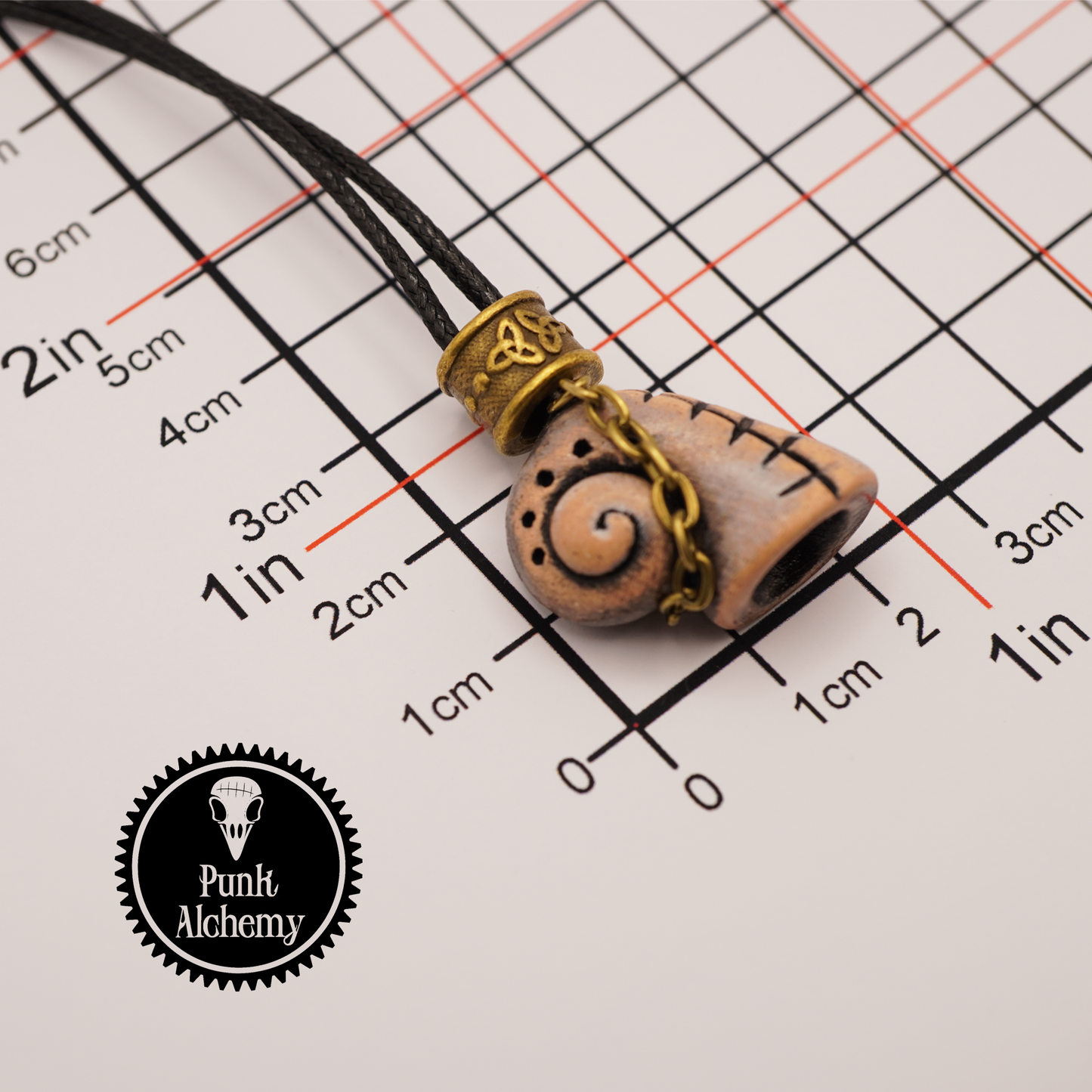 Necklace with a pendant on a grid background, featuring the 'Punk Alchemy' brand.