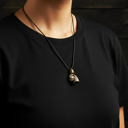 Person wearing a black shirt with a necklace featuring a unique pendant.