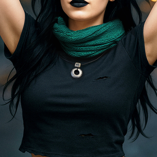 Handmade ceramic ring pendant on a black cord worn with a black top and green knitted scarf.