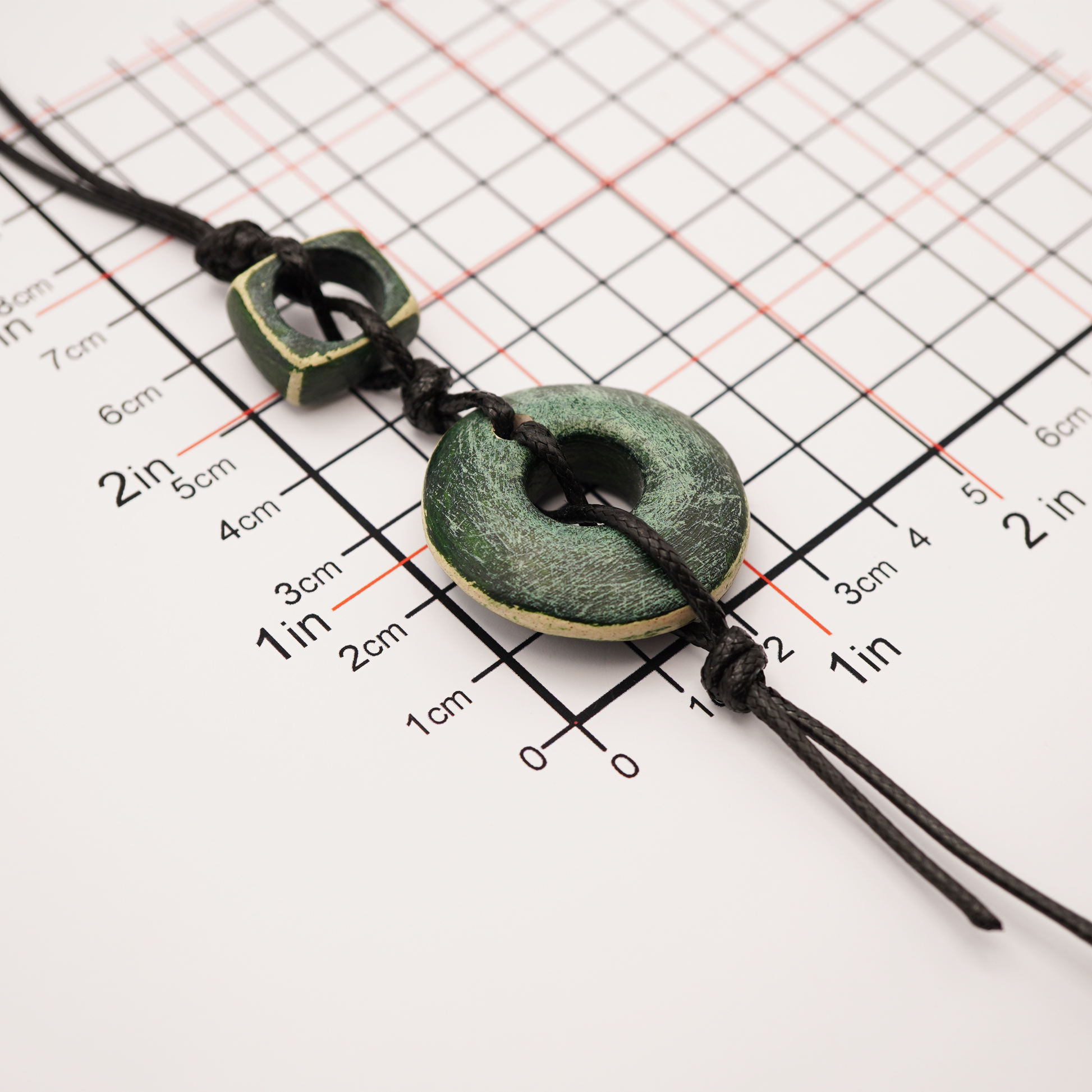 Necklace with green ceramic beads on a grid background for measurement