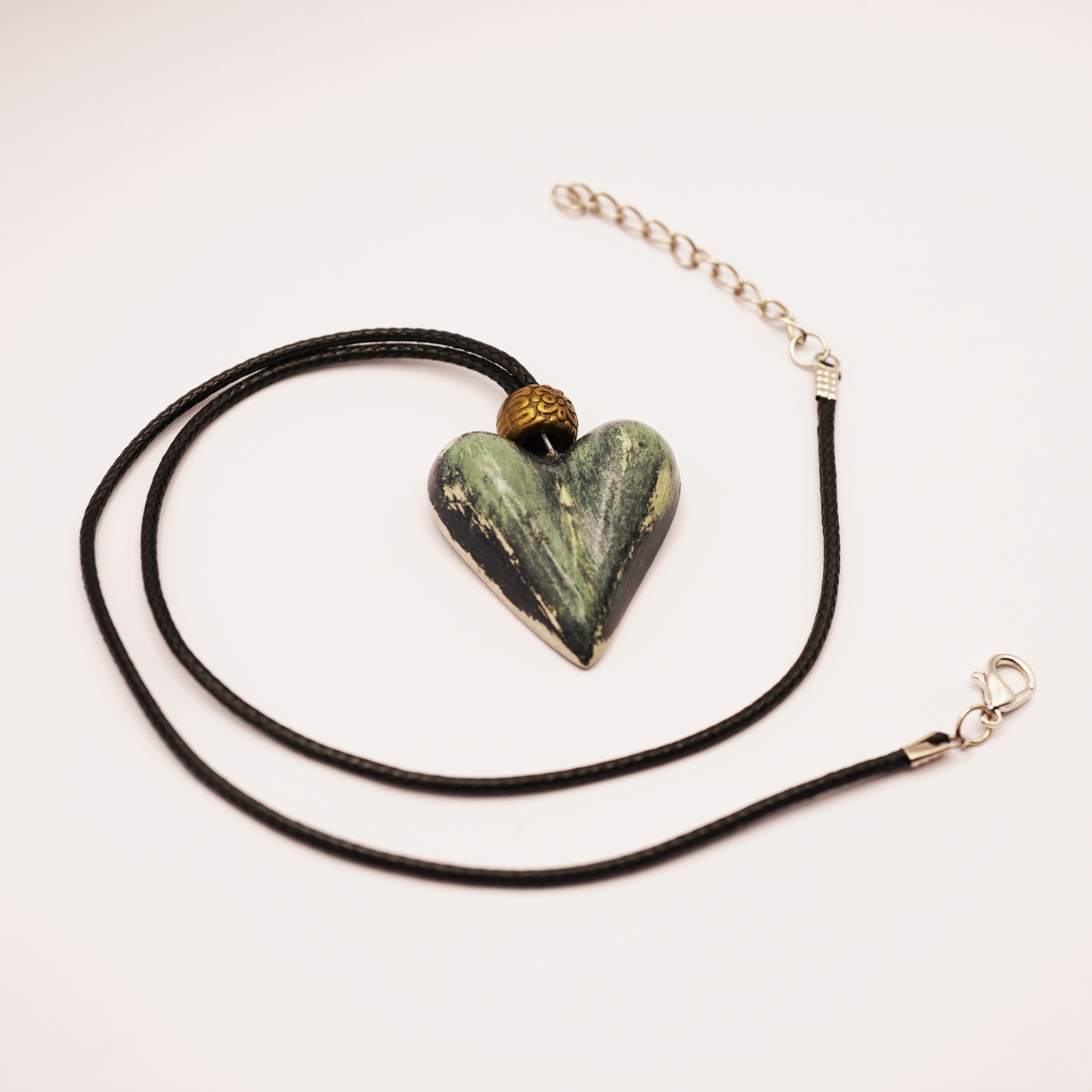 Necklace with a heart-shaped green stone pendant on a white background