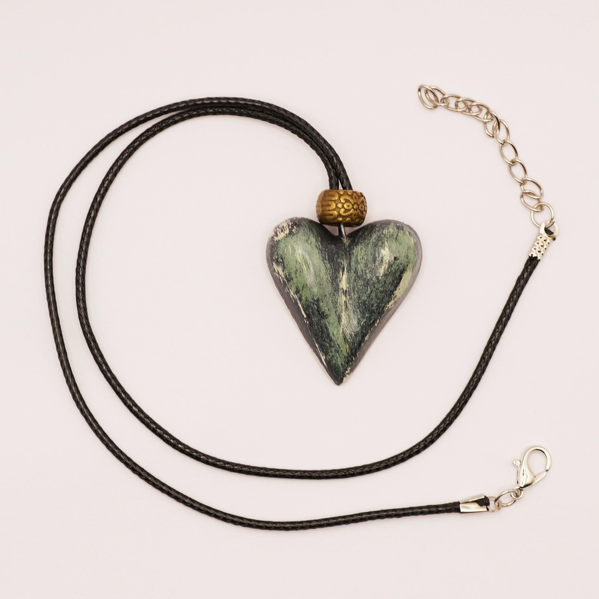 Heart-shaped stone pendant on a black cord with gold accents against a light background
