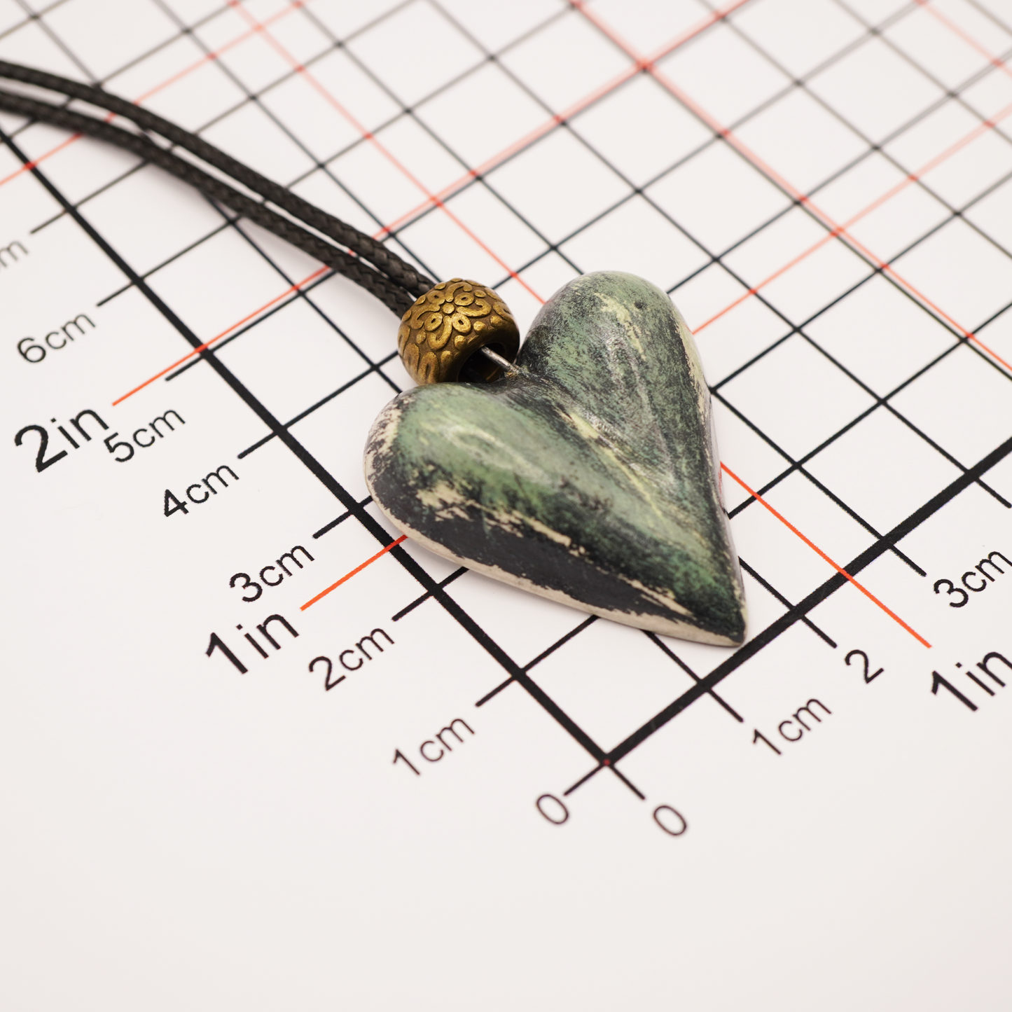Heart-shaped pendant on a cord with measurement scale